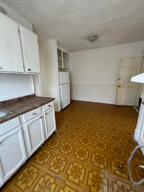 a kitchen with white cabinets and a wooden floor