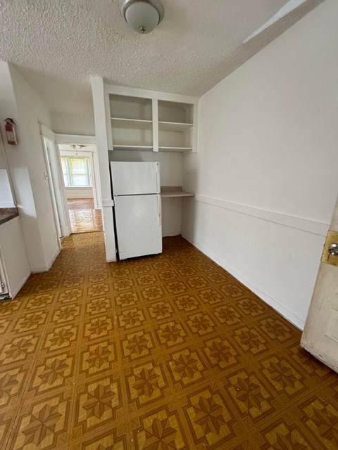 an empty kitchen with a refrigerator and shelves