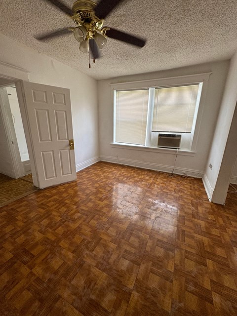 an empty living room with wood floors and a ceiling fan