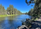 a river with trees on either side and a blue sky