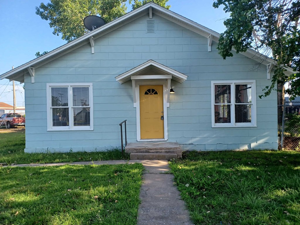 the front of a blue house with a yellow door
