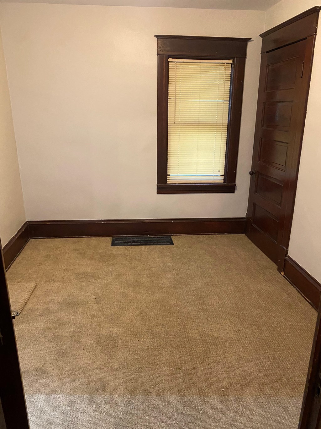 an empty room with a carpet and a window