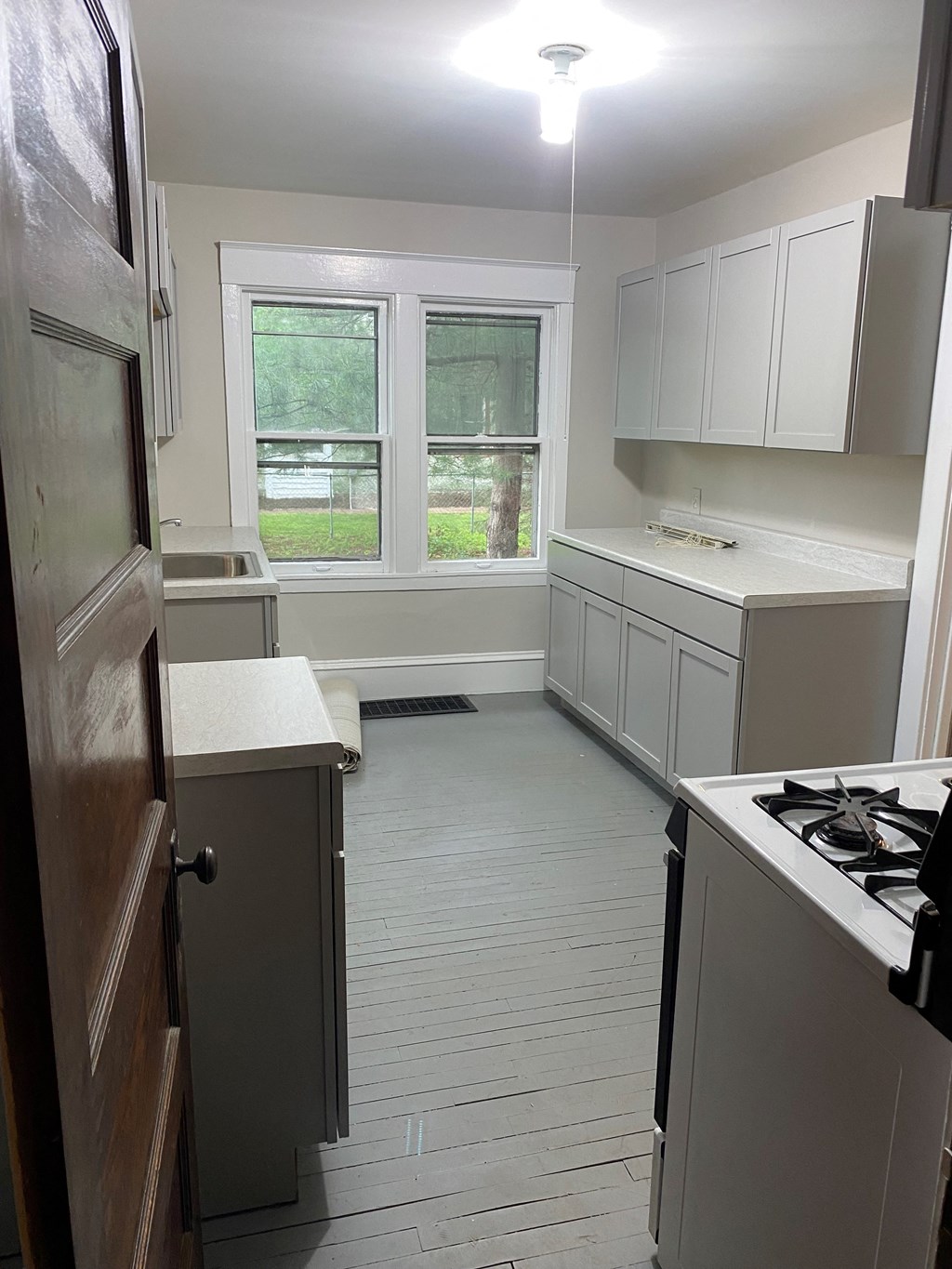 a kitchen with white cabinets and a stove and a window