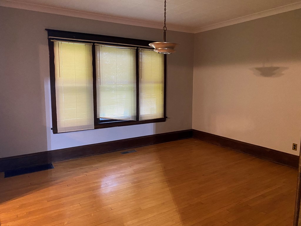 an empty living room with wood floors and a window