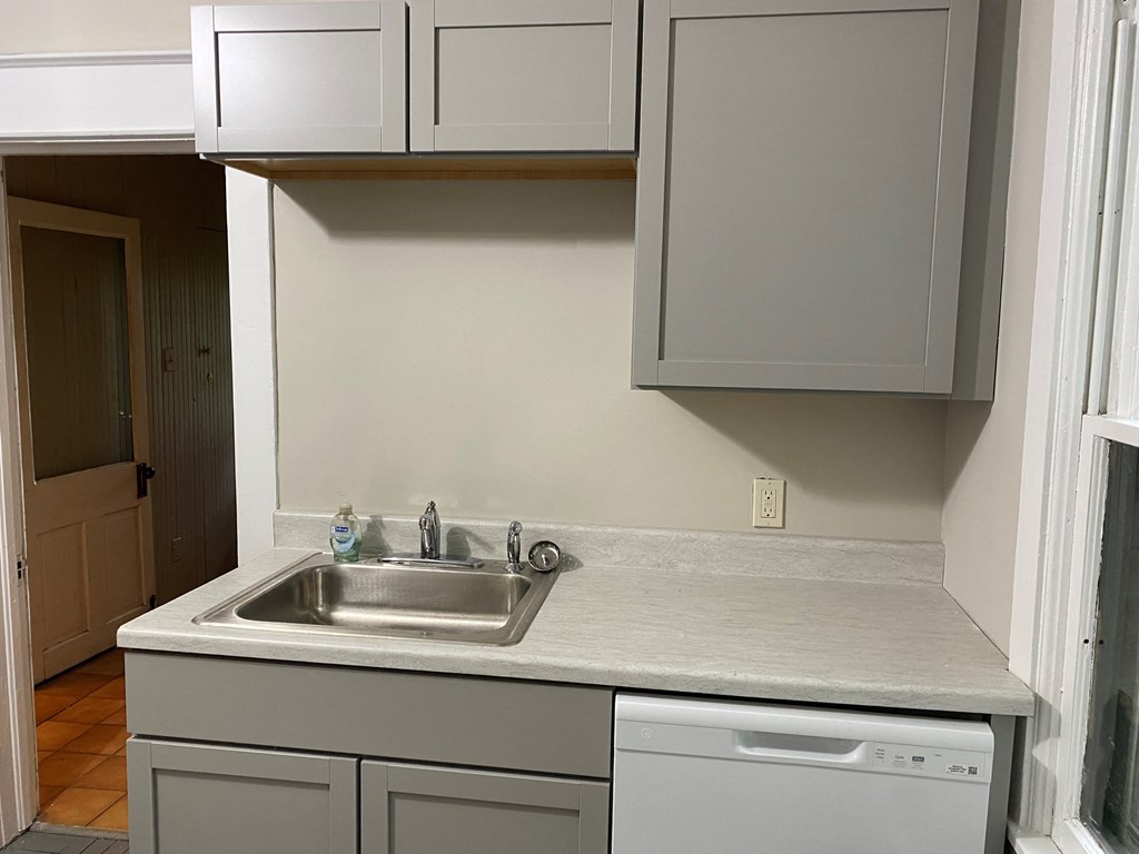 an empty kitchen with white cabinets and a sink