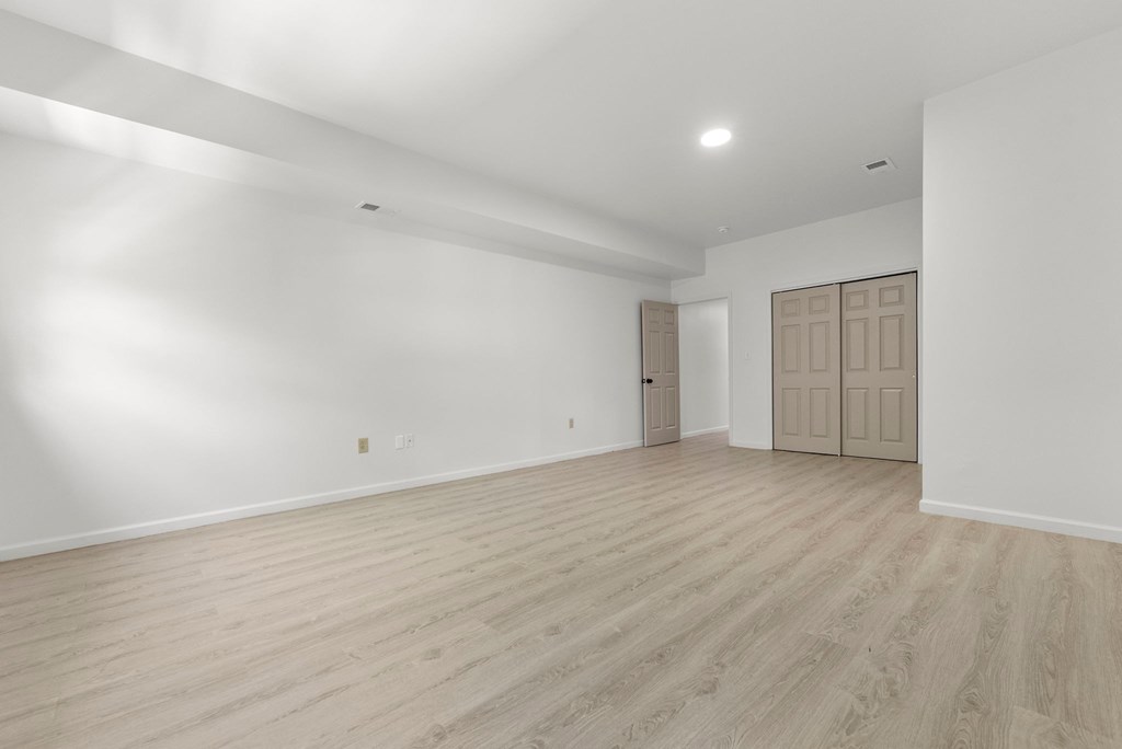 a living room with white walls and wooden floors and a door