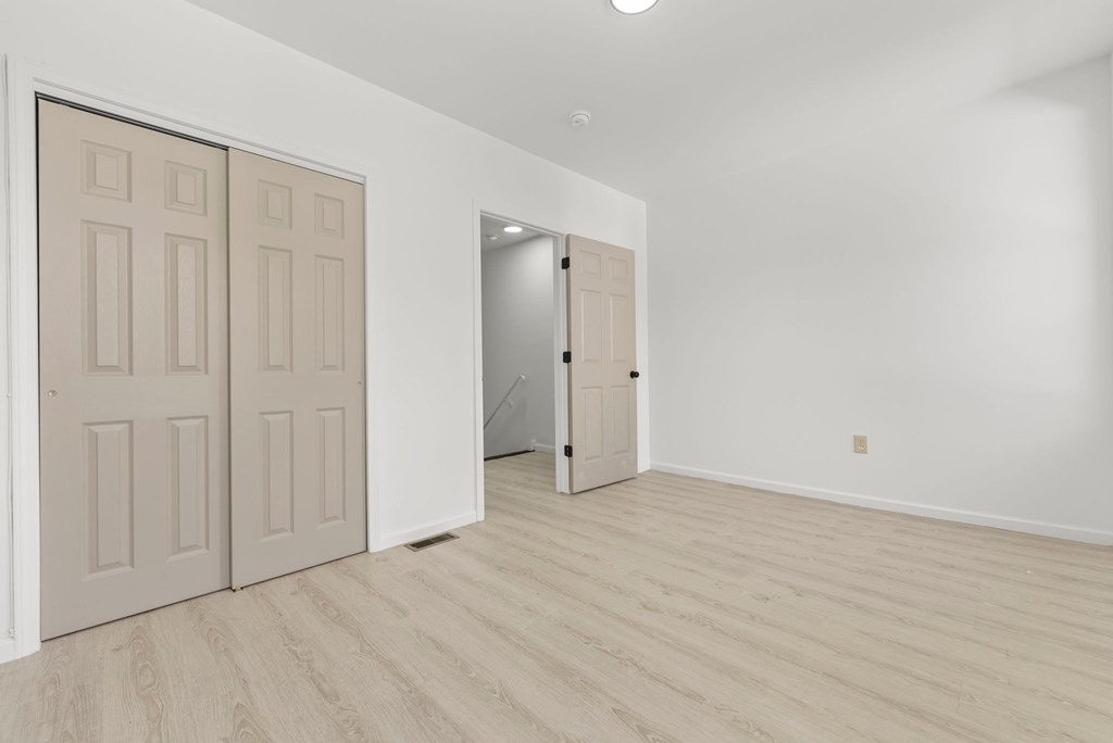 a bedroom with white walls and white doors and a door to a closet