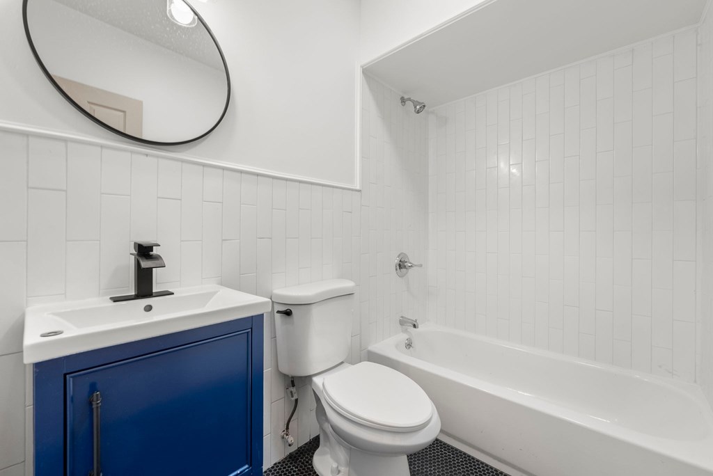 a white bathroom with a blue cabinet and a toilet