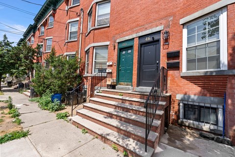 the front of a brick house with stairs and a green door