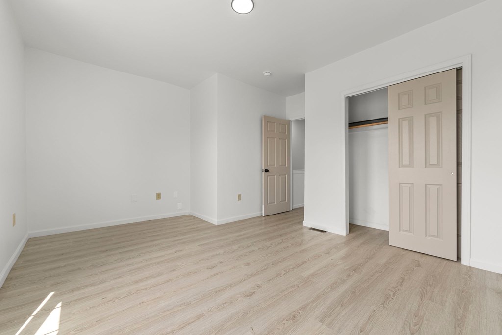 a living room with white walls and a door to a closet