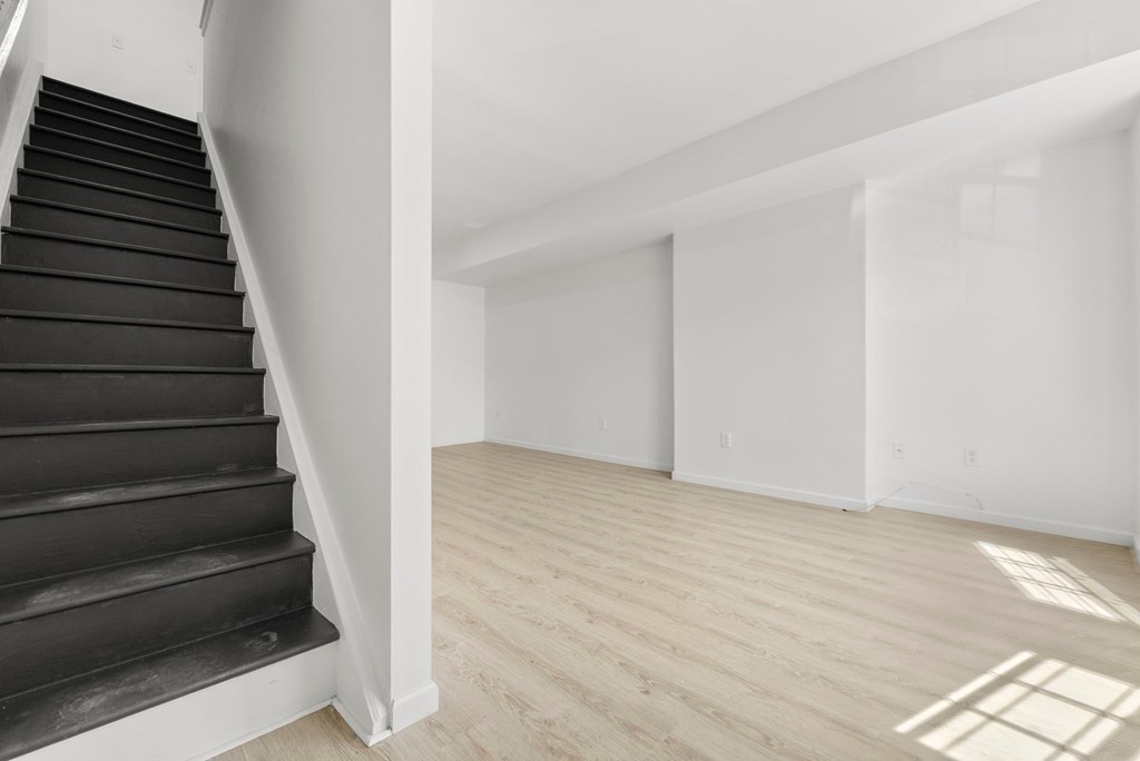 a renovated living room with black stairs and white walls