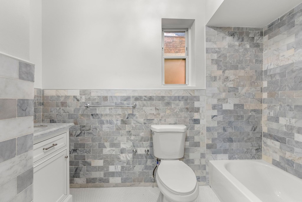 a bathroom with a toilet and a tub and a window