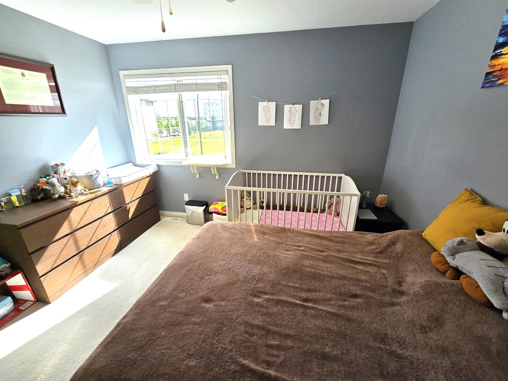 a bedroom with a bed and a crib and a dresser and a window