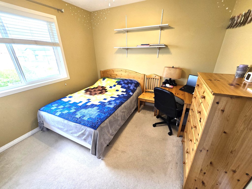 a bedroom with a bed and a desk with a computer