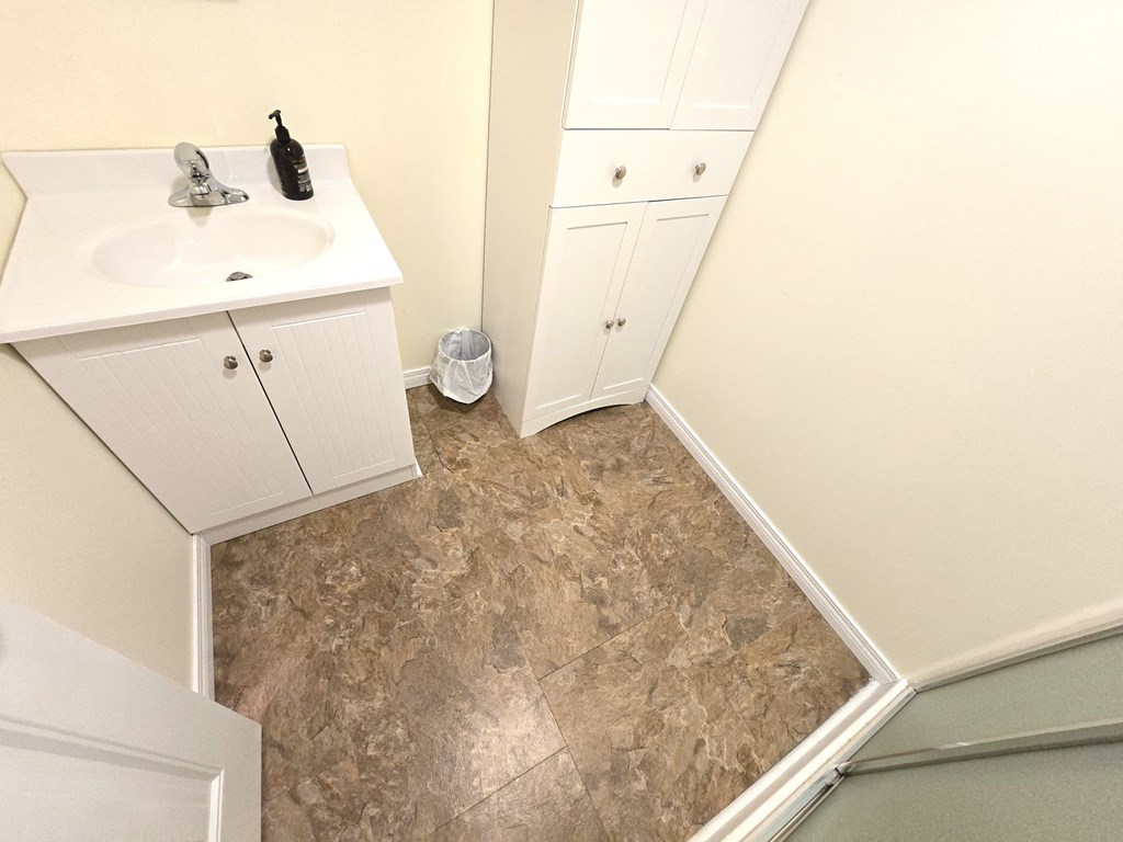 a bathroom with a sink and a shower and a tiled floor