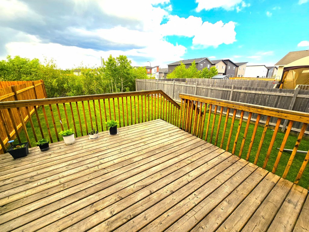 a backyard deck with potted plants and a blue sky