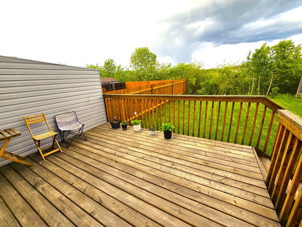 a backyard deck with chairs and a privacy fence