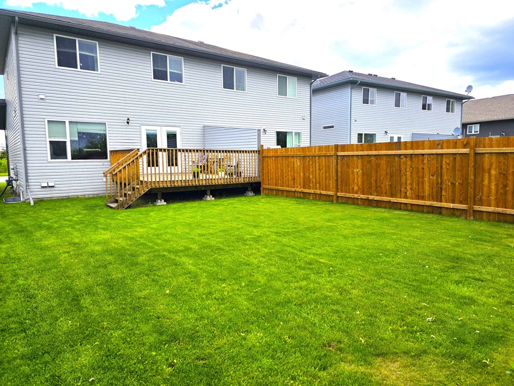 a backyard with a wooden fence in front of a house