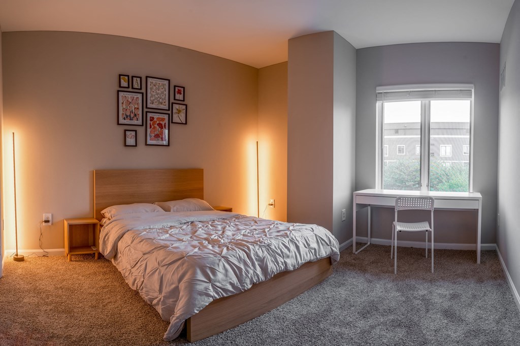 a bedroom with a bed and a desk and a window