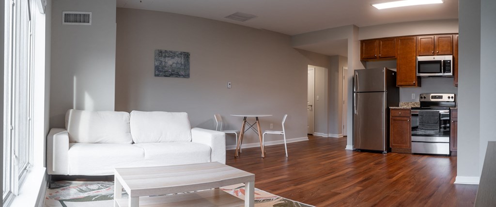 an empty living room with a white couch and a kitchen