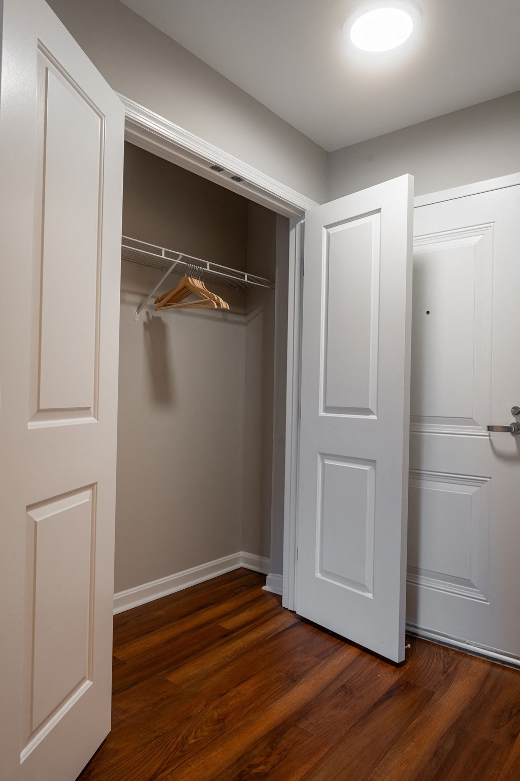 an empty closet with a wooden floor and white doors