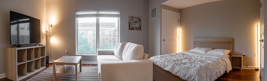 a bedroom with a bed and a chair and a window