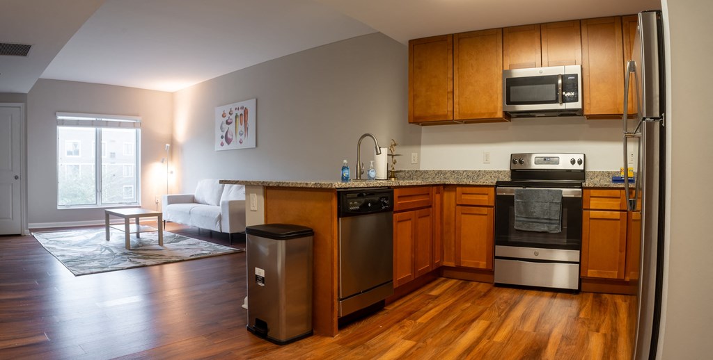 a kitchen with wooden cabinets and appliances and a living room with a couch