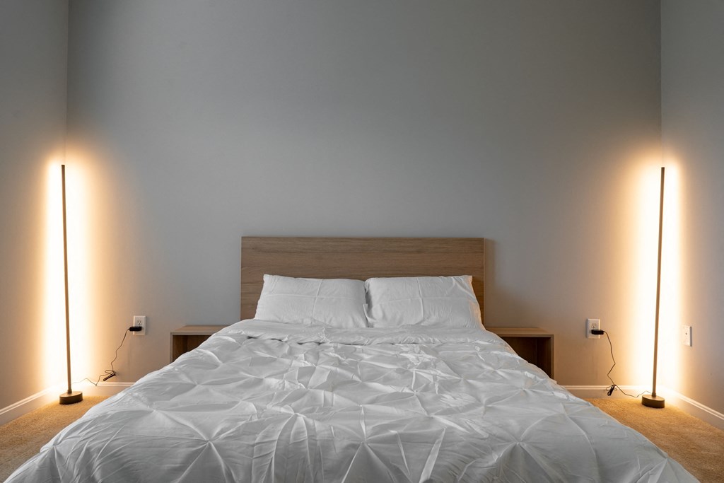 a bedroom with a bed and two lamps on the sides of it