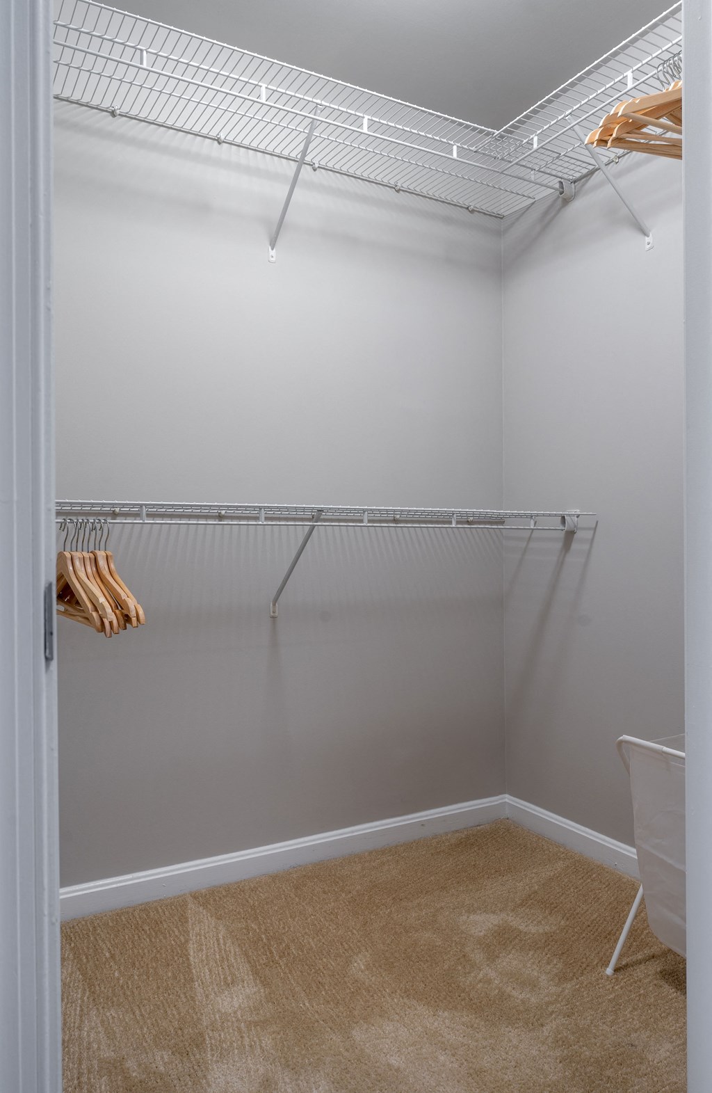 a walk in closet in a home with white walls and a white closet with shelves