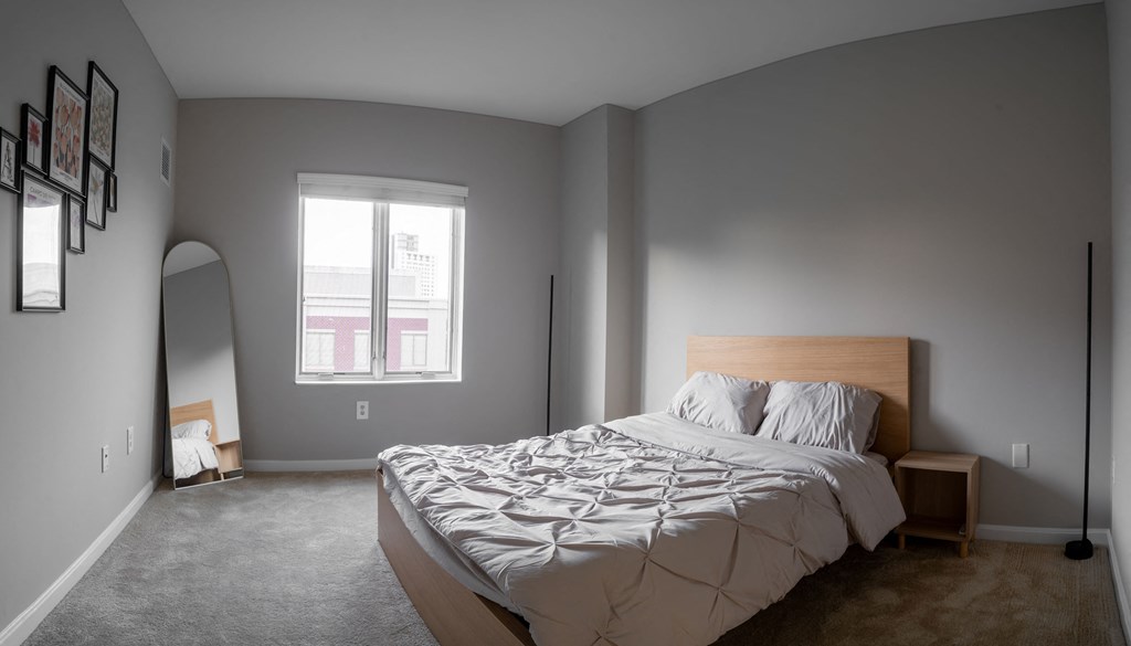a bedroom with grey walls and a bed and a window