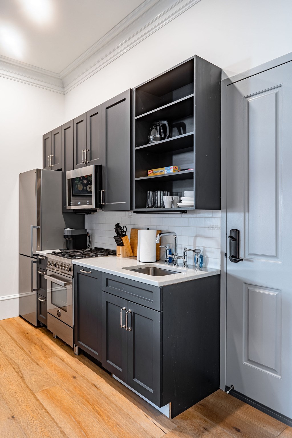 a kitchen with gray cabinets and a sink and a refrigerator