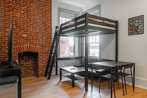 a loft bed in a living room with a red brick fireplace and a dining table