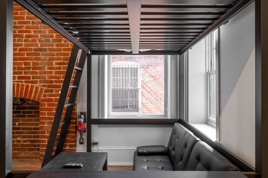 a living room with lofted ceilings and a brick wall