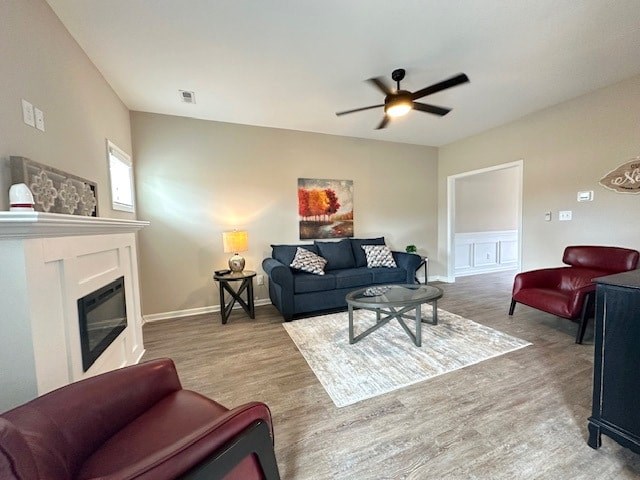 A living room with a fireplace, two couches, and a ceiling fan.