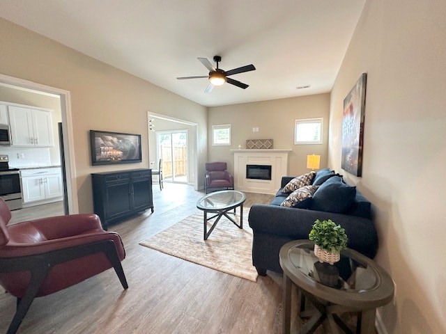 A living room with a red chair, a black couch, and a ceiling fan.