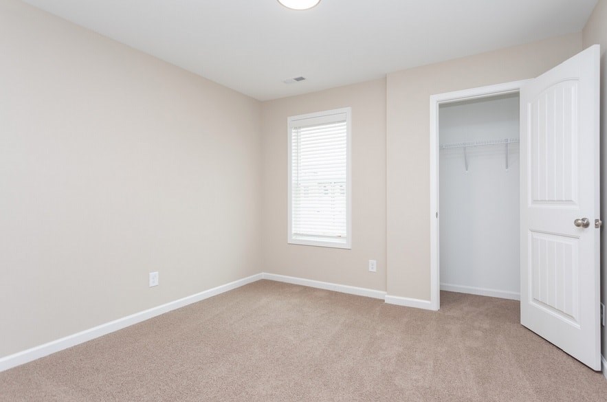 A room with a white door and a window with blinds.