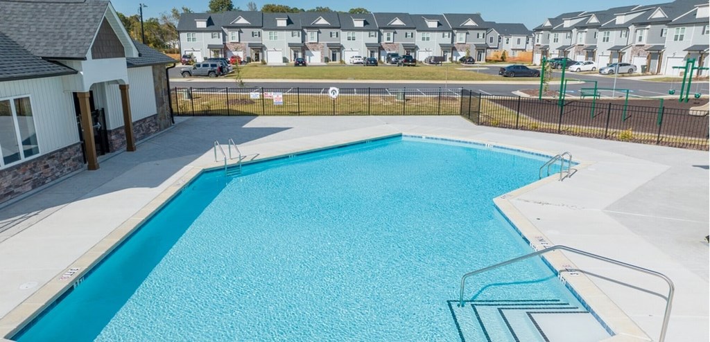 A blue swimming pool with a diving board and a small building next to it.