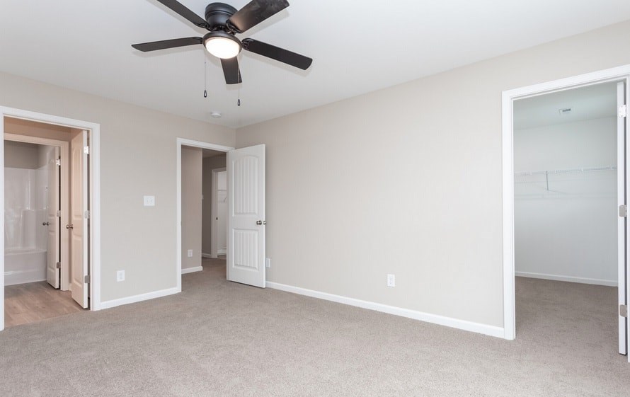A room with a ceiling fan and carpeted floor.
