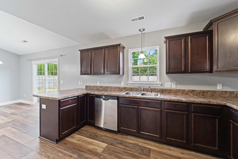 A kitchen with dark wood cabinets and a granite countertop.
