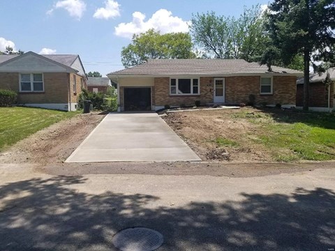 a small brick house with a sidewalk in front of it