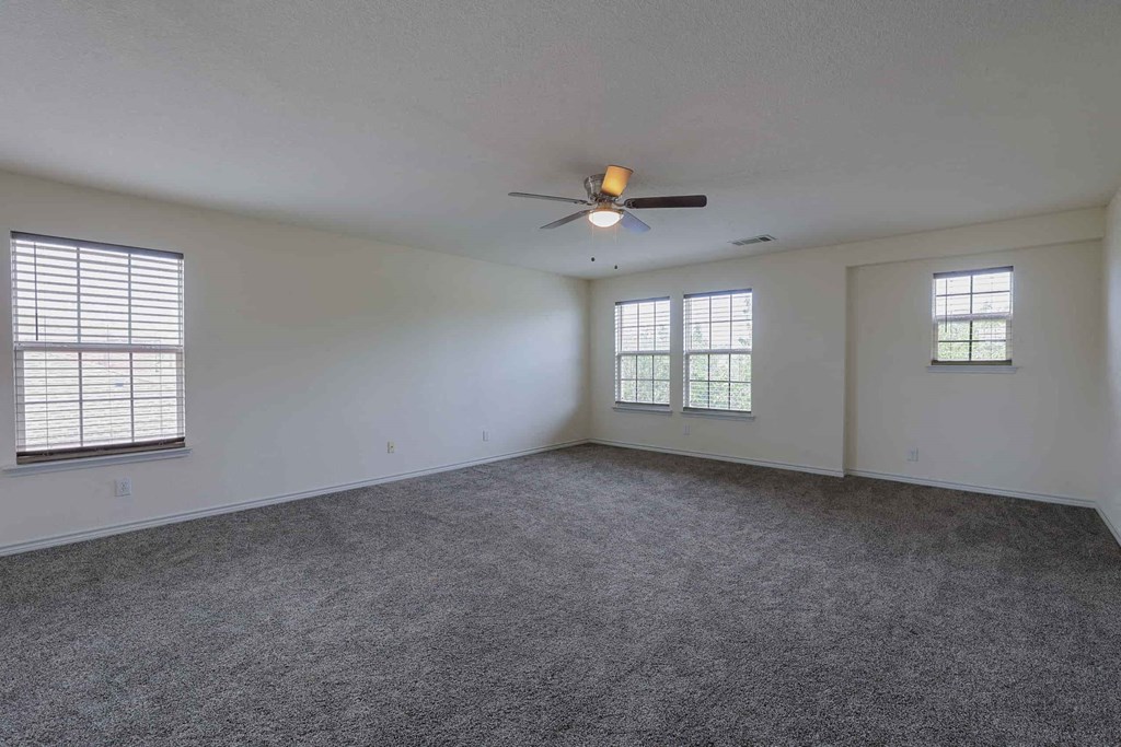 an empty living room with a ceiling fan and a window