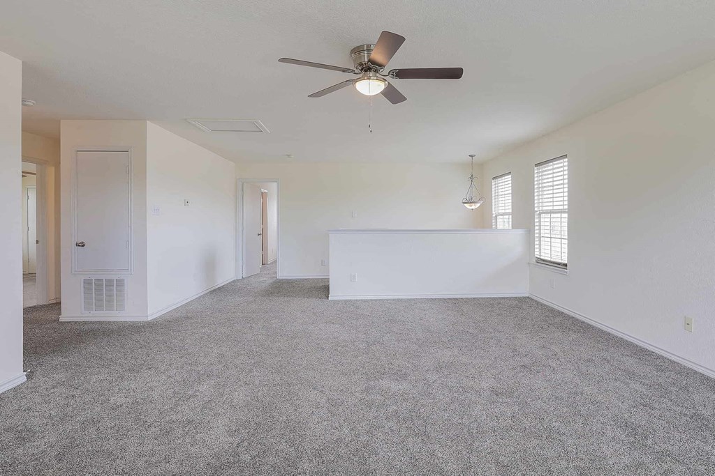 an empty living room with a ceiling fan