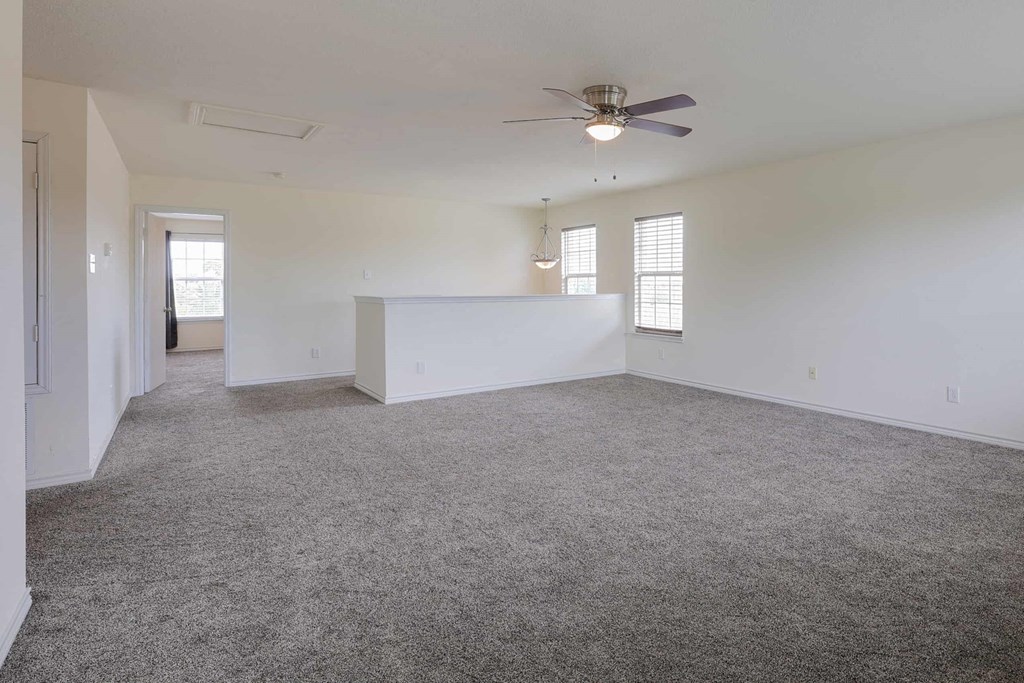 an empty living room with carpet and a ceiling fan