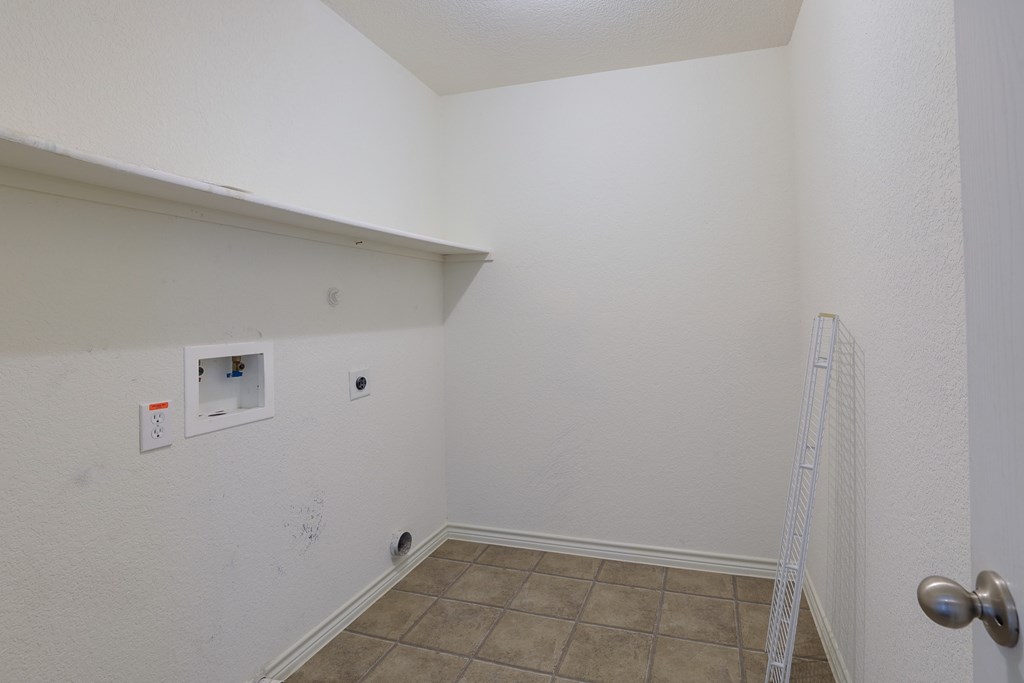 an empty room with a white wall and tile floor