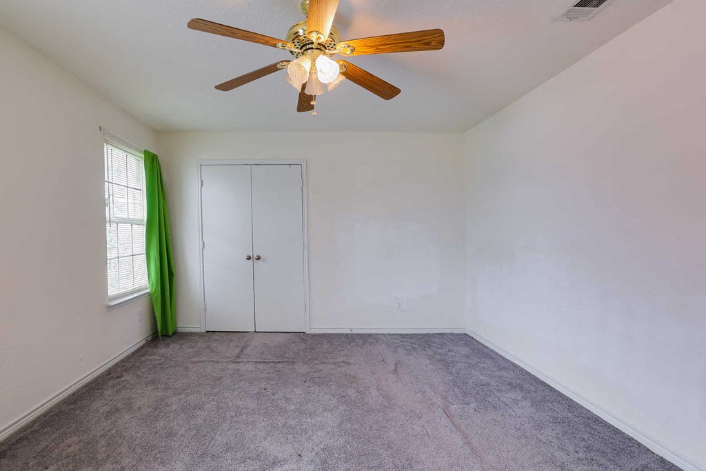 an empty room with a ceiling fan and a closet