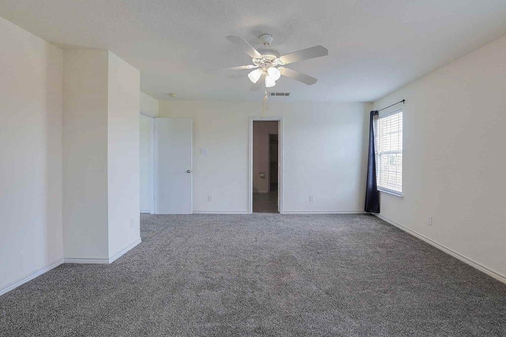 an empty living room with a ceiling fan