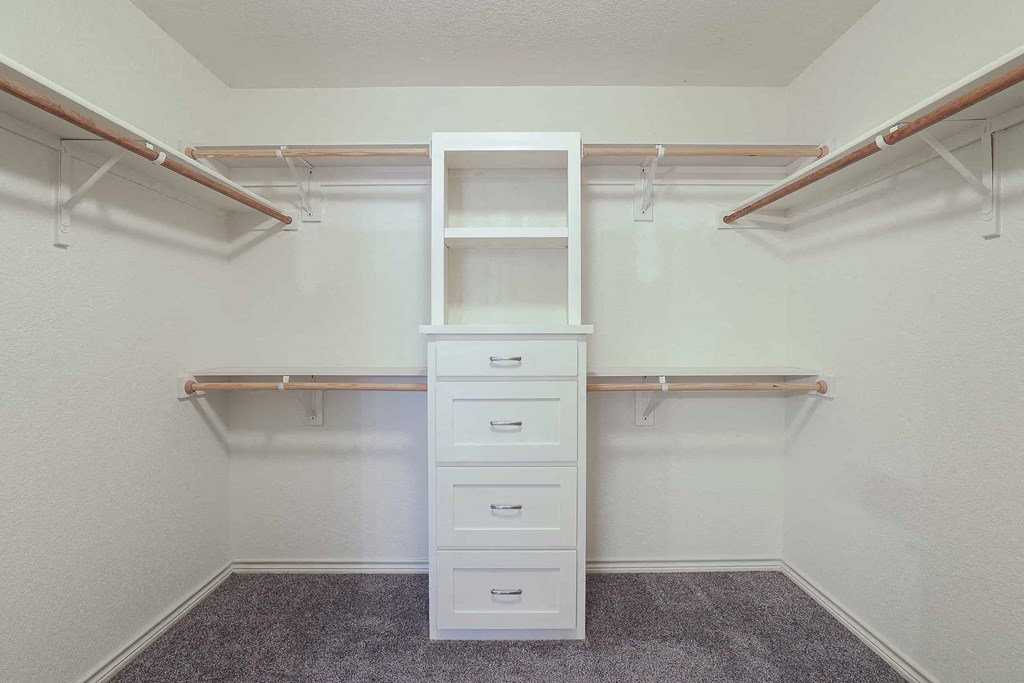 a walk in closet with shelves and drawers