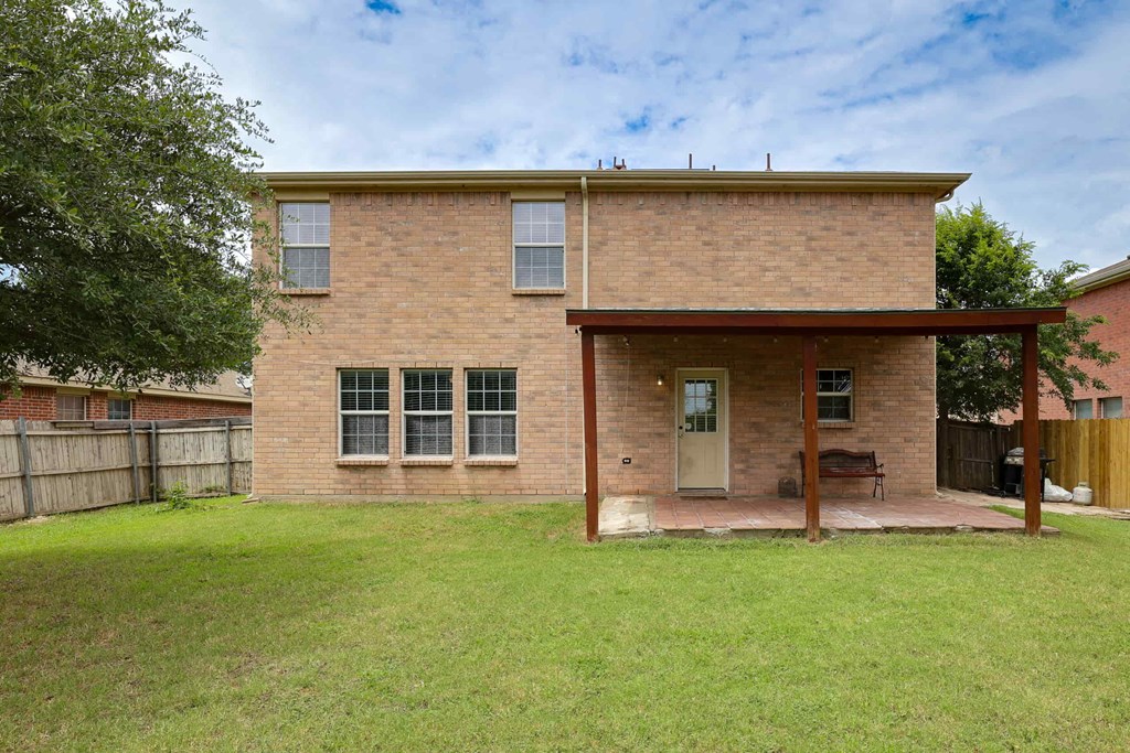 the front of a brick house with a yard and a porch