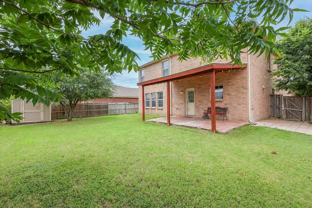 the backyard of a brick house with a yard and a patio
