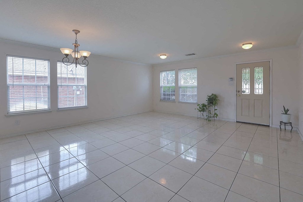 an empty living room with a door and three windows